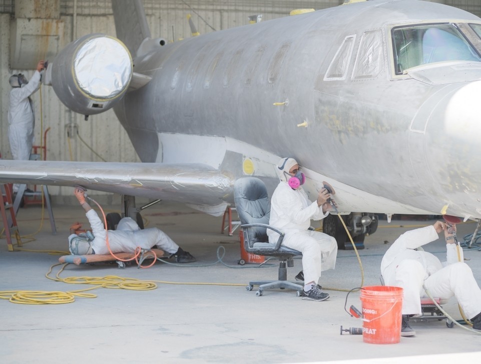 An MRO shop's paint team work on the body of a private jet