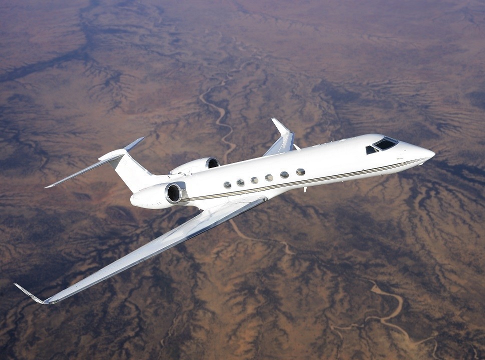 A Gulfstream private jet flying across desert landscape