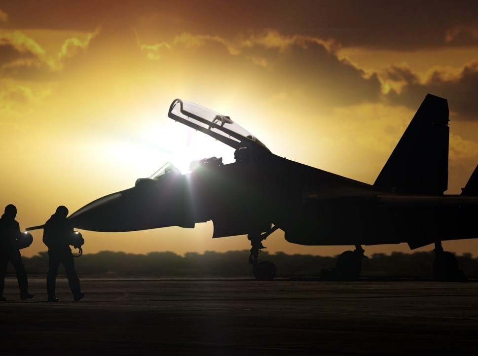 Pilots walking towards fighter jet at sunrise