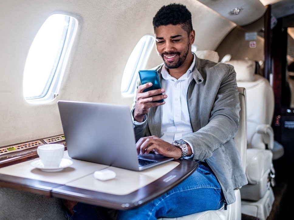 Business man using his phone and laptop in a private jet cabin