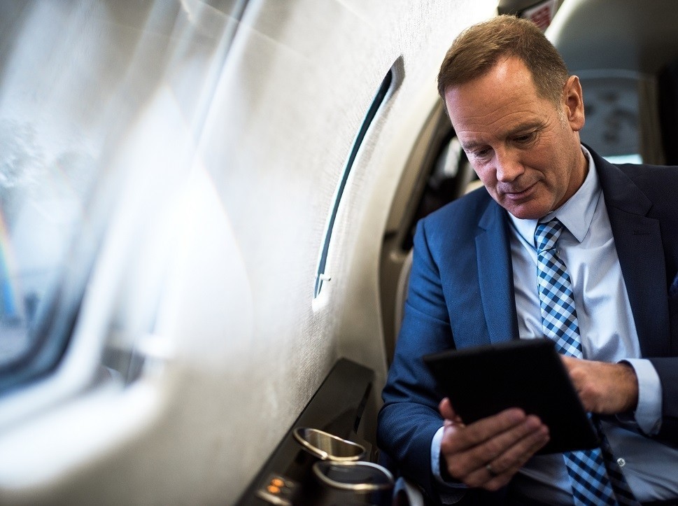 Businessman with iPad in private jet cabin