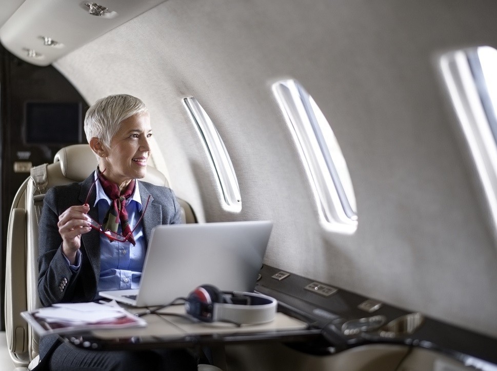 A businesswoman with laptop smiles aboard a private jet