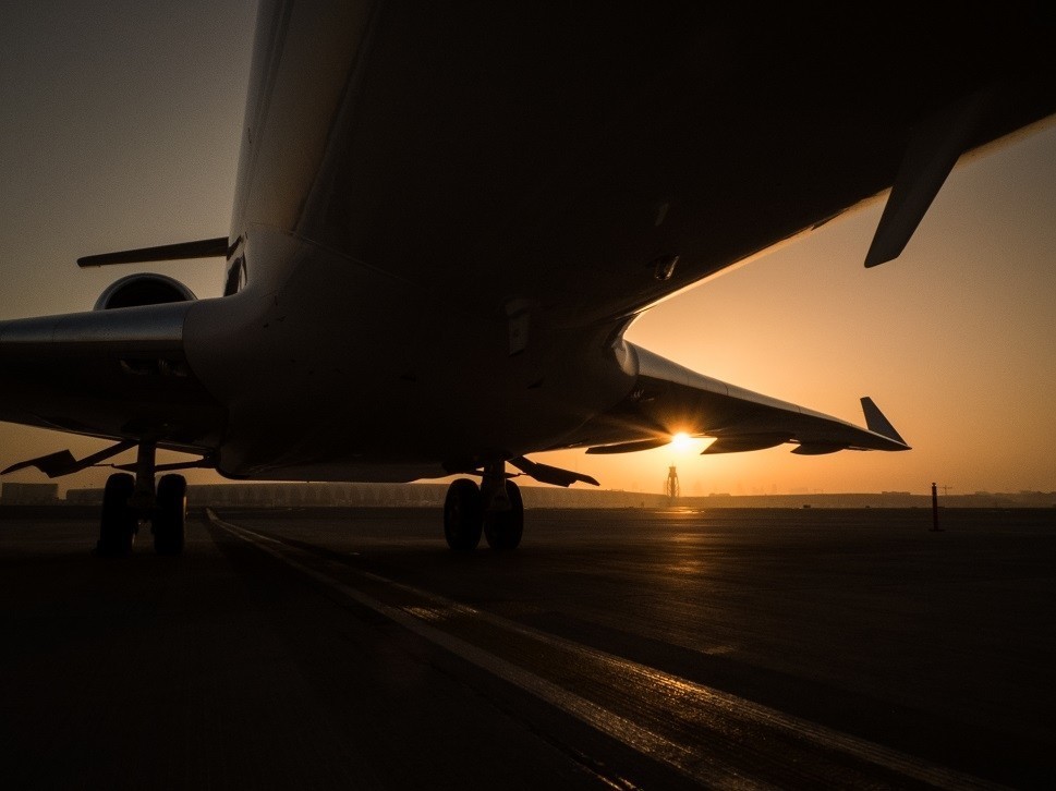 Looking across an empty airport ramp from beneath a private jet
