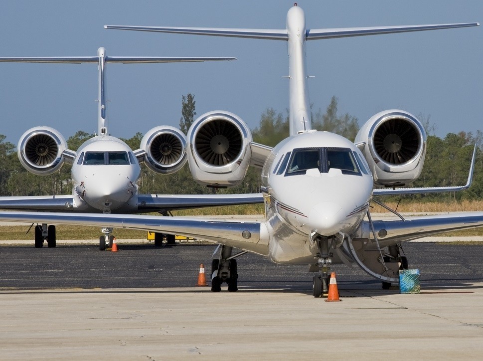 Private jets lined up on an airport ramp