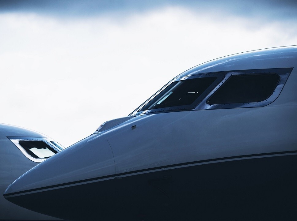 Two large private jets parked nose-to-nose 