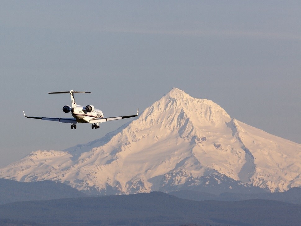 Mid-size private jet landing in front of mountains