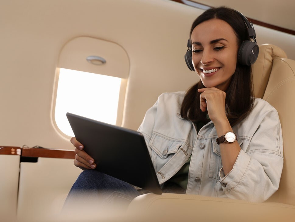 Woman using electronic device on private jet with headphones