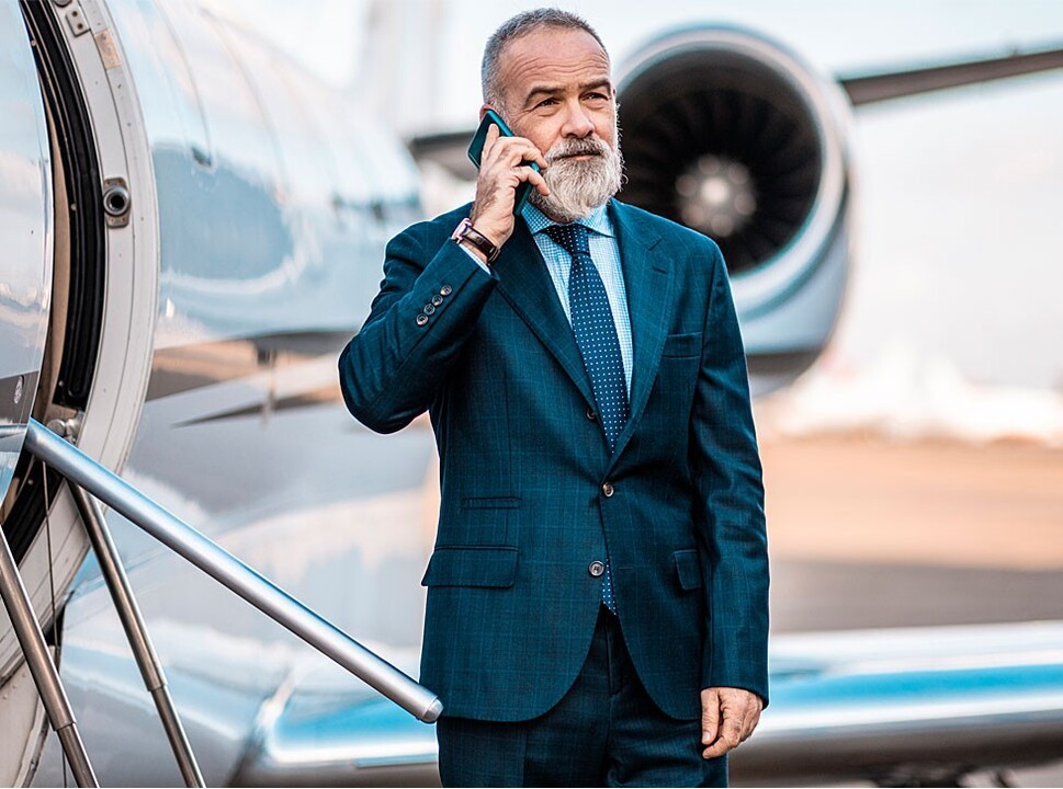 Businessman speaking on cell phone outside private jet
