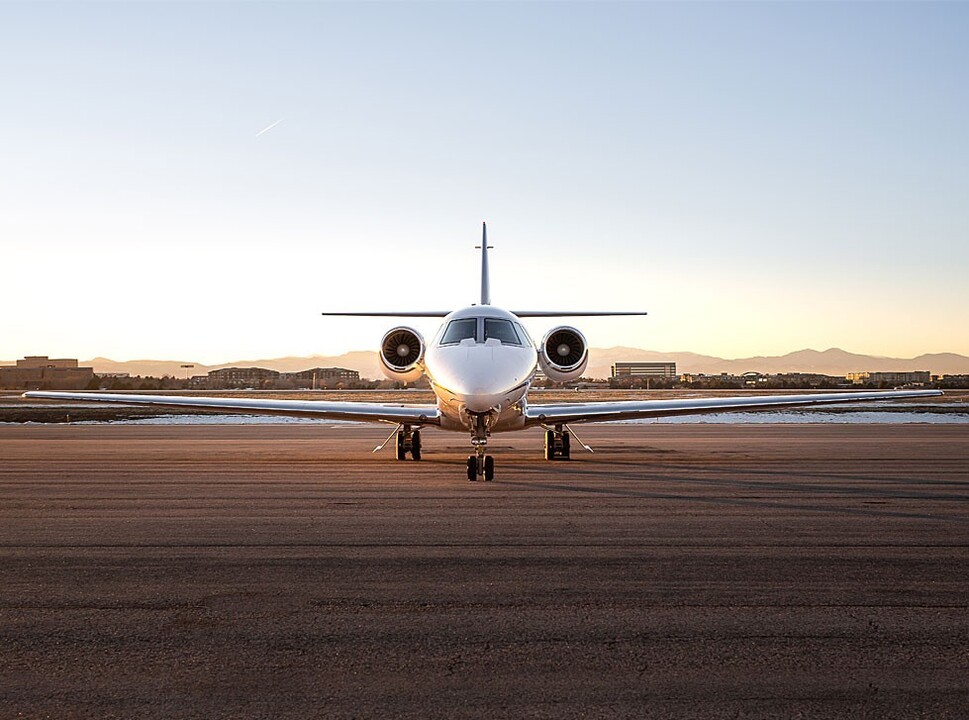 Private jet parked on empty ramp at sunrise