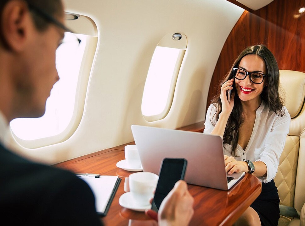Businesspeople at work on a private jet using satellite connectivity