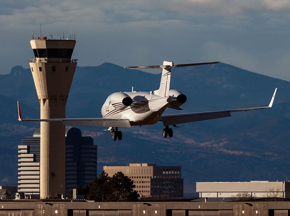 Private jet landing in front of an ATC tower